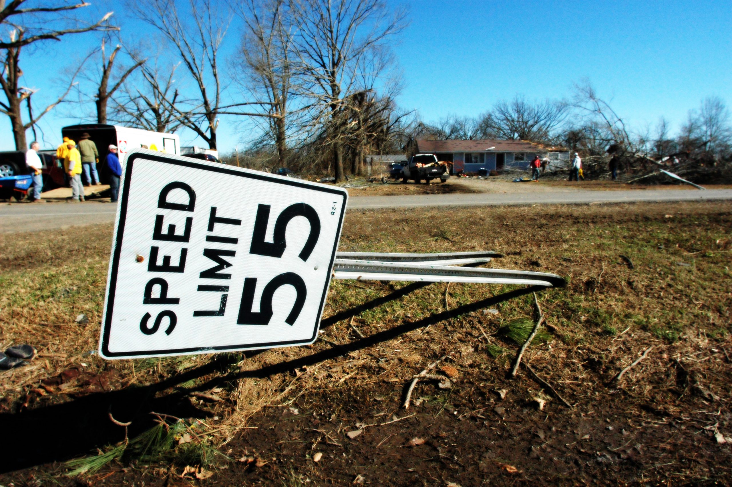 February 8, 2008, Polk County, AR -- Highway sign bent by tornado which swept the state. Church volunteers in the bacground attempt to salvage valuables from house which was destroyed. The Federal Emergency Managment Agency (FEMA) works closely with volunteer agencies to provide much needed help in the immediate aftermath of a disaster. Leif Skoogfors/FEMA